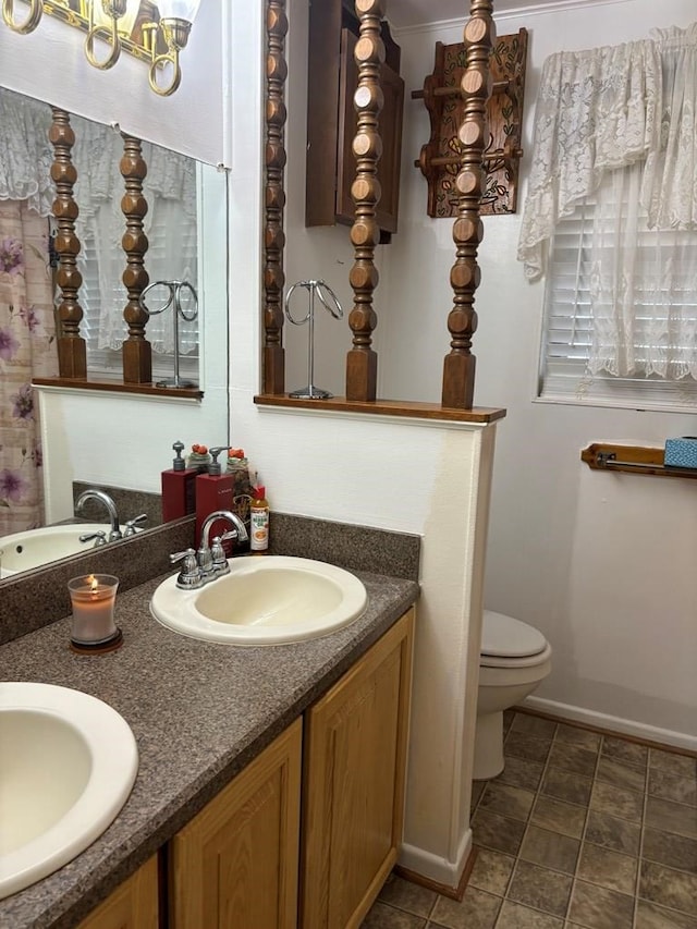 297 County Rd 221, Snyder, TX 79549 - bathroom with baseboards, toilet, a sink, and double vanity