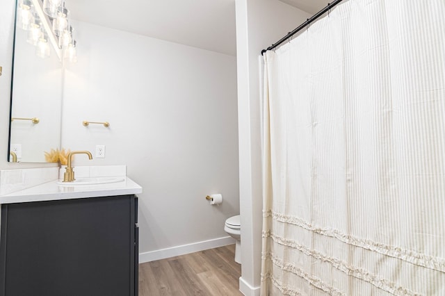 bathroom with wood finished floors, toilet, vanity, baseboards, and curtained shower