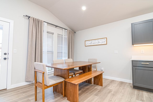 dining area featuring lofted ceiling, light wood-style flooring, and baseboards