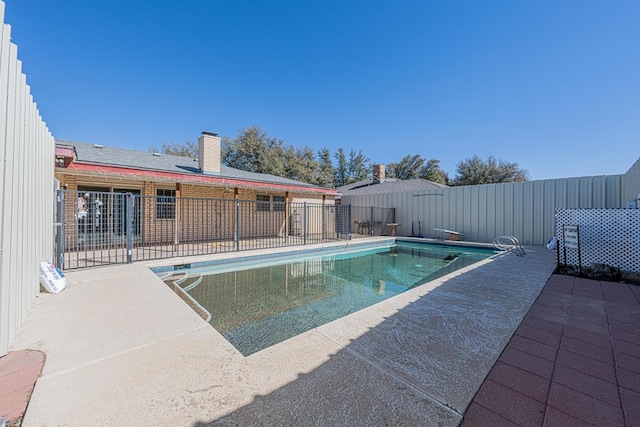 view of swimming pool featuring fence, a diving board, a fenced in pool, and a patio