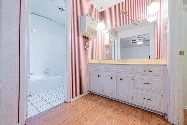 full bath with wood finished floors, visible vents, vanity, and wallpapered walls