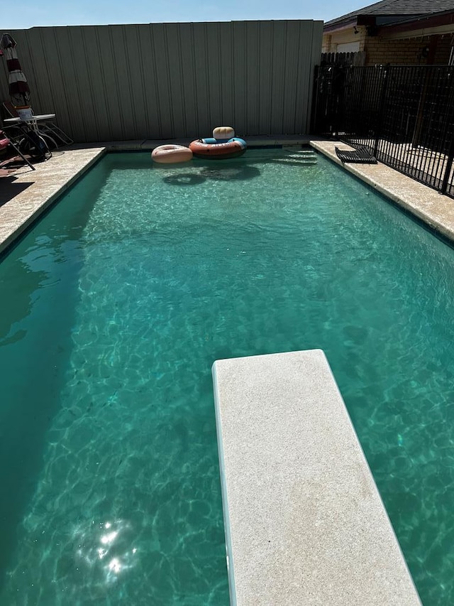 view of pool featuring fence, a diving board, and a fenced in pool