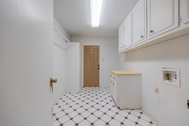 laundry area featuring a textured ceiling, light floors, washer hookup, and cabinet space