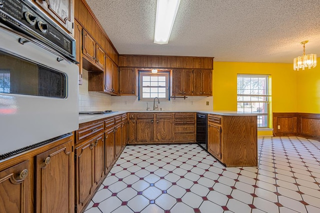 kitchen with white oven, light floors, a sink, beverage cooler, and a peninsula