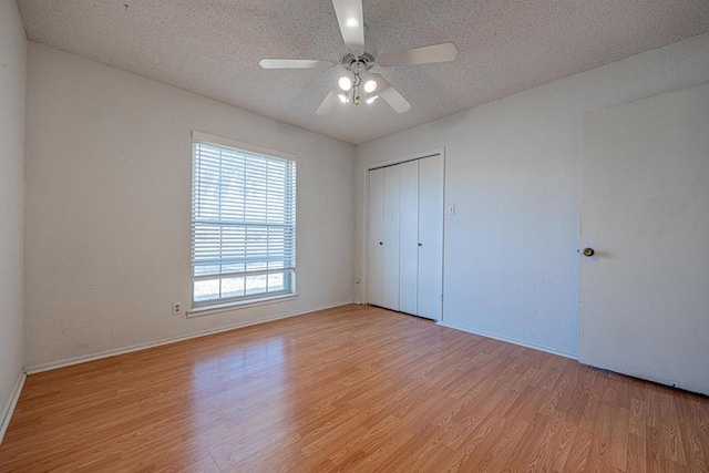 unfurnished bedroom featuring a textured ceiling, light wood finished floors, a closet, and a ceiling fan