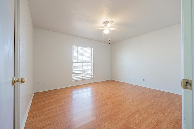 empty room with ceiling fan, light wood-style flooring, and baseboards