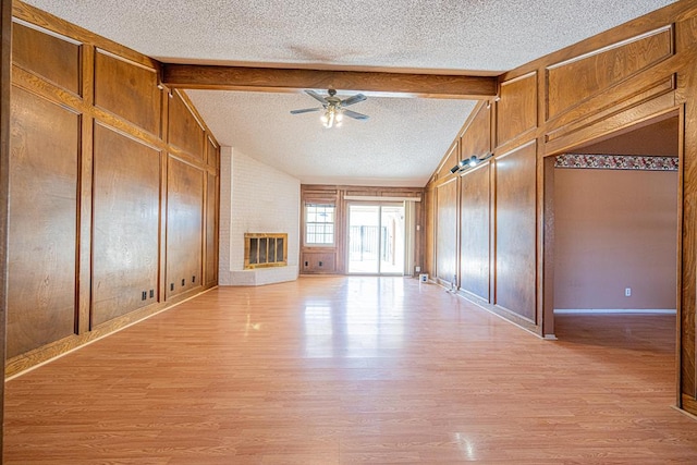 unfurnished living room featuring vaulted ceiling with beams, a textured ceiling, a fireplace, a ceiling fan, and light wood-style floors