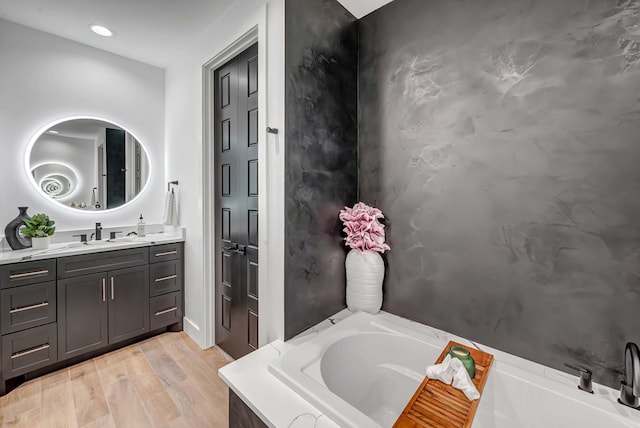 bathroom with wood-type flooring, a bath, and vanity