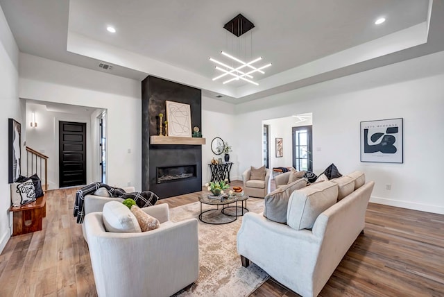 living room featuring a raised ceiling, hardwood / wood-style flooring, and a fireplace