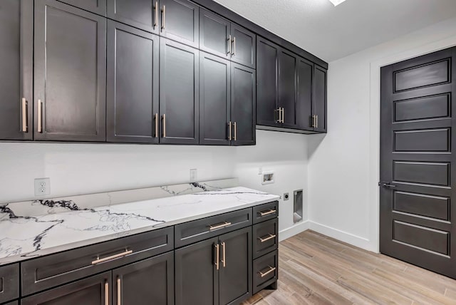 laundry room featuring electric dryer hookup, hookup for a washing machine, light hardwood / wood-style floors, and cabinets