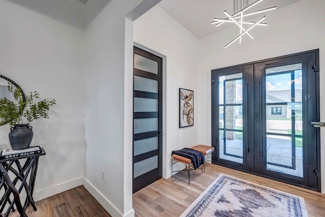 doorway with hardwood / wood-style floors, a chandelier, and french doors