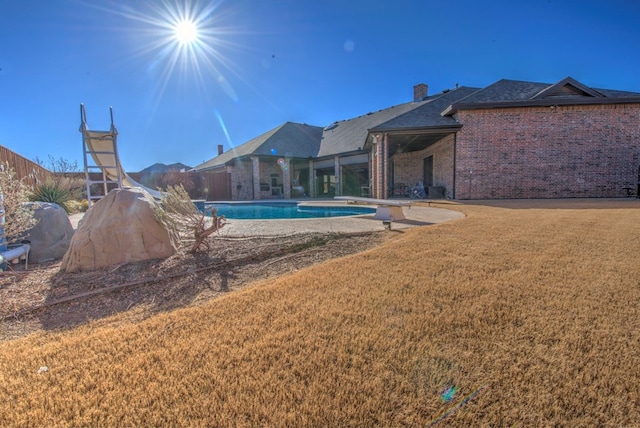 view of pool featuring a diving board and a lawn