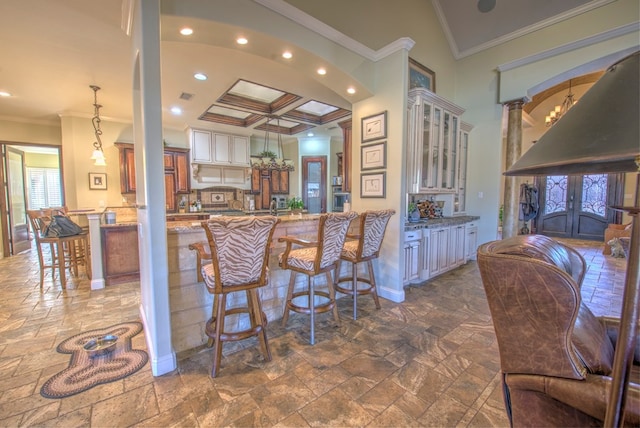 kitchen featuring a breakfast bar area, hanging light fixtures, ornamental molding, coffered ceiling, and kitchen peninsula