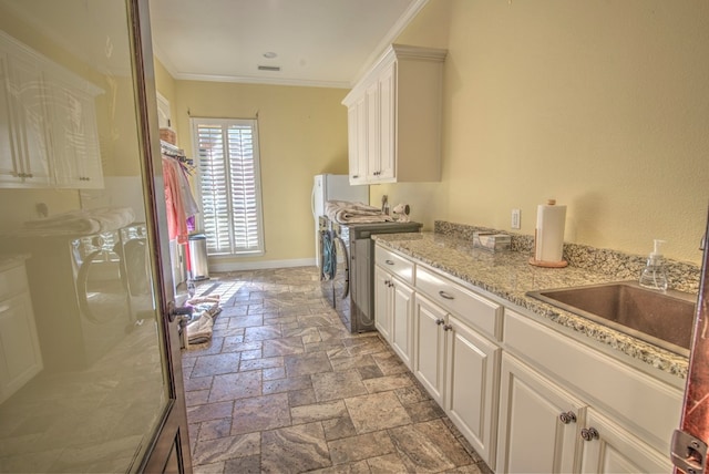 laundry room with crown molding, cabinets, sink, and washing machine and clothes dryer