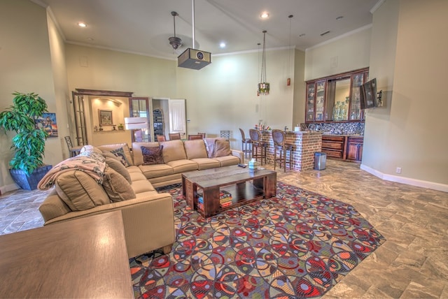 living room with a towering ceiling, ornamental molding, and indoor bar