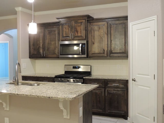 kitchen featuring a breakfast bar, appliances with stainless steel finishes, dark brown cabinetry, and sink