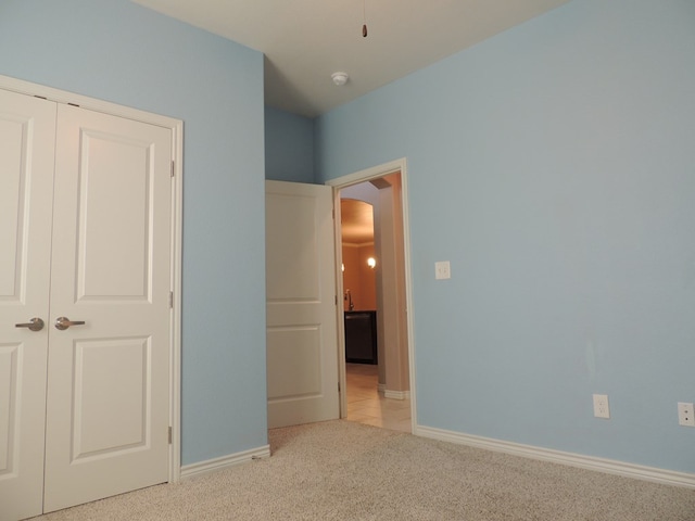 unfurnished bedroom with light colored carpet and a closet