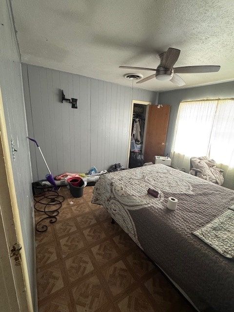 bedroom featuring ceiling fan, a textured ceiling, dark parquet floors, and a closet