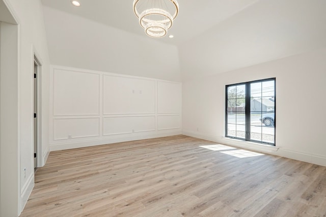 interior space with a towering ceiling, light hardwood / wood-style floors, and a notable chandelier