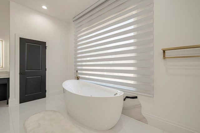 bathroom featuring vanity, a healthy amount of sunlight, and a tub to relax in