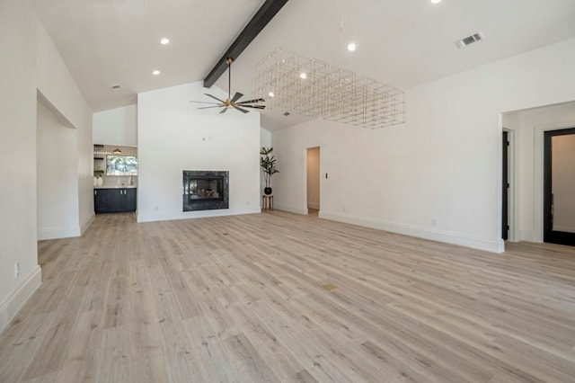 unfurnished living room with high vaulted ceiling, beamed ceiling, light hardwood / wood-style floors, and ceiling fan