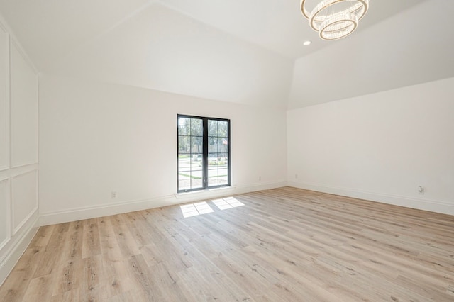 spare room with high vaulted ceiling, a notable chandelier, and light wood-type flooring