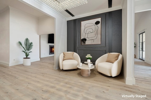 sitting room with ornamental molding and light hardwood / wood-style flooring