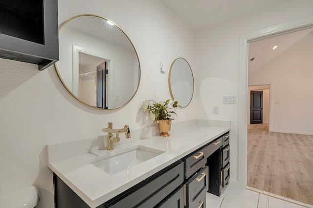 bathroom featuring vanity, vaulted ceiling, wood-type flooring, and toilet