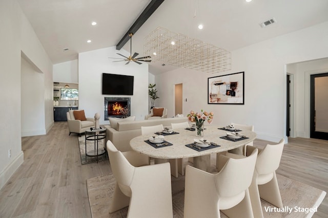 dining space with ceiling fan, beam ceiling, high vaulted ceiling, and light hardwood / wood-style flooring