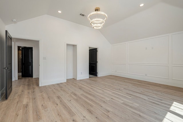 interior space featuring vaulted ceiling, an inviting chandelier, and light hardwood / wood-style flooring