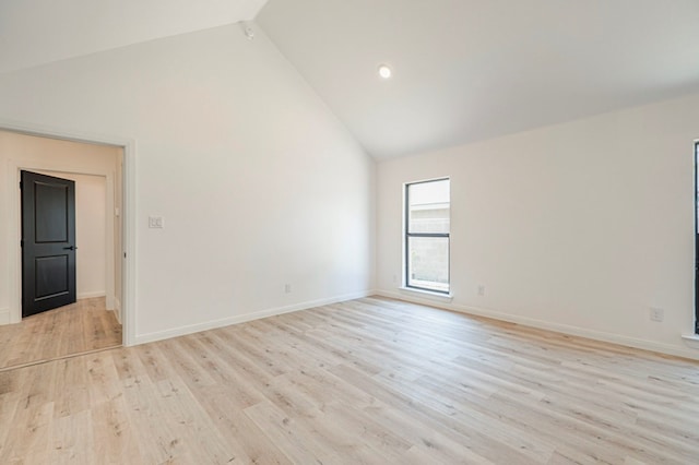 empty room with high vaulted ceiling and light hardwood / wood-style floors