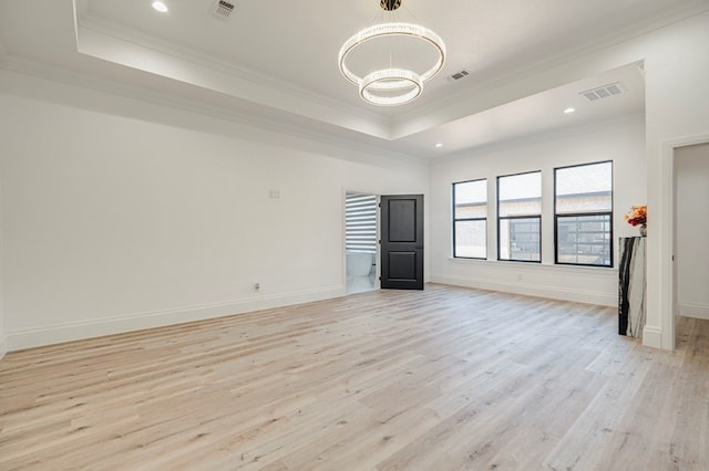 interior space featuring a notable chandelier, crown molding, a raised ceiling, and light wood-type flooring