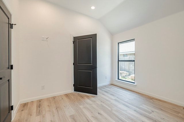 spare room with lofted ceiling and light wood-type flooring