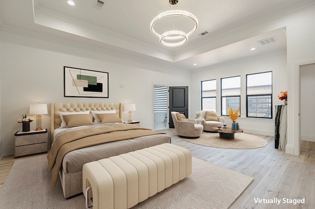 bedroom featuring crown molding, a tray ceiling, a chandelier, and light wood-type flooring