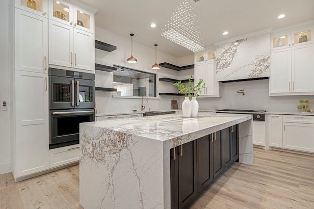 kitchen with white cabinetry, light stone countertops, double oven, and hanging light fixtures