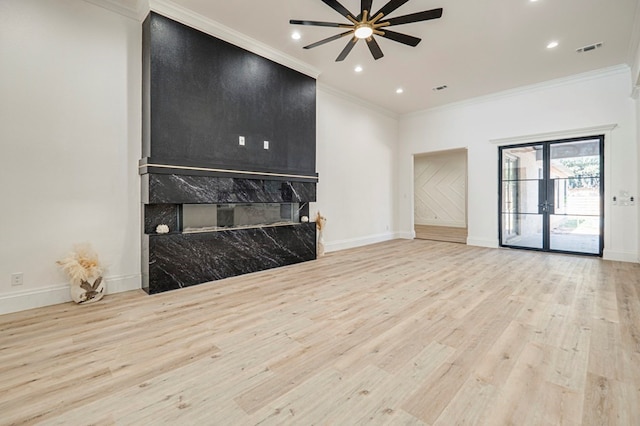 living room with ornamental molding, a high end fireplace, ceiling fan, and light hardwood / wood-style floors