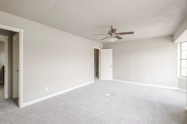 spare room featuring carpet floors, ceiling fan, a textured ceiling, and baseboards