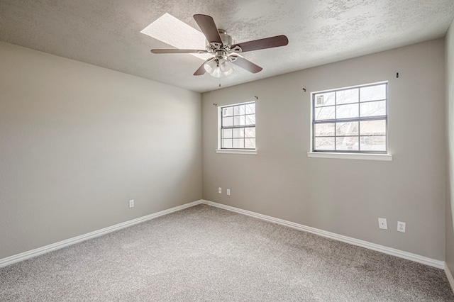 carpeted empty room with ceiling fan, a textured ceiling, and baseboards