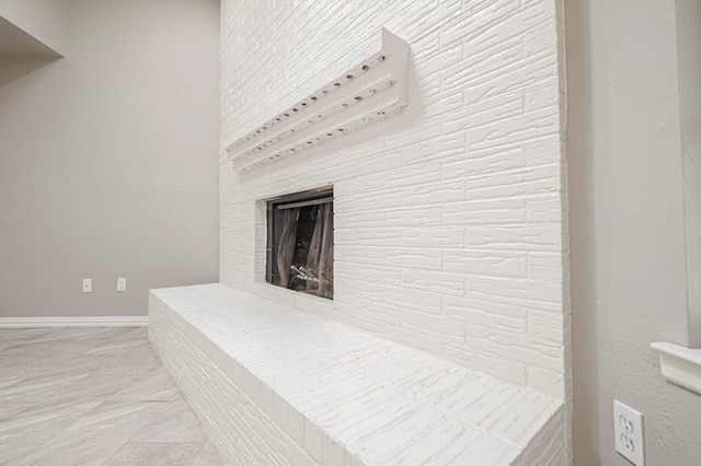 interior details featuring a fireplace with raised hearth and baseboards