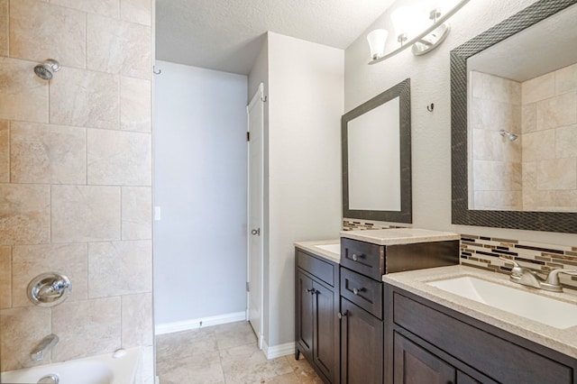 full bath with baseboards, decorative backsplash, a textured ceiling, washtub / shower combination, and a sink