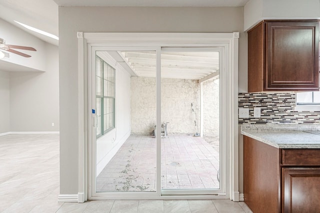 doorway featuring ceiling fan and baseboards