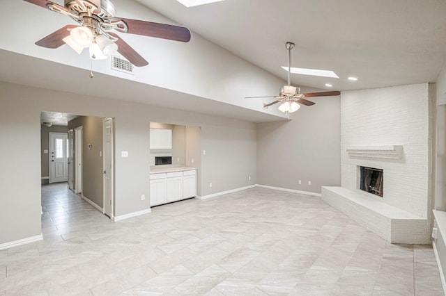 unfurnished living room featuring a skylight, baseboards, visible vents, a brick fireplace, and high vaulted ceiling