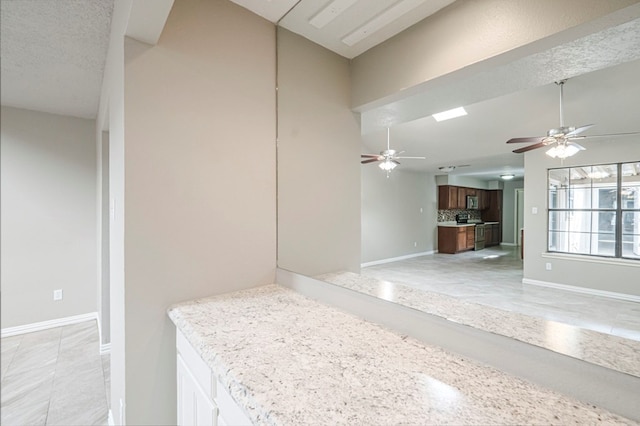 interior space with lofted ceiling, ceiling fan, tasteful backsplash, and baseboards