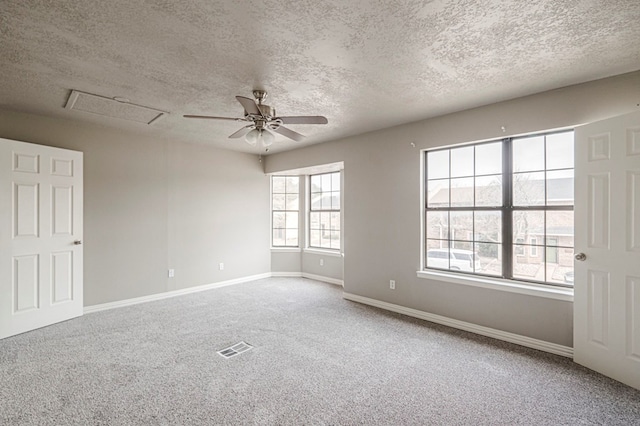 carpeted spare room with visible vents, attic access, ceiling fan, a textured ceiling, and baseboards