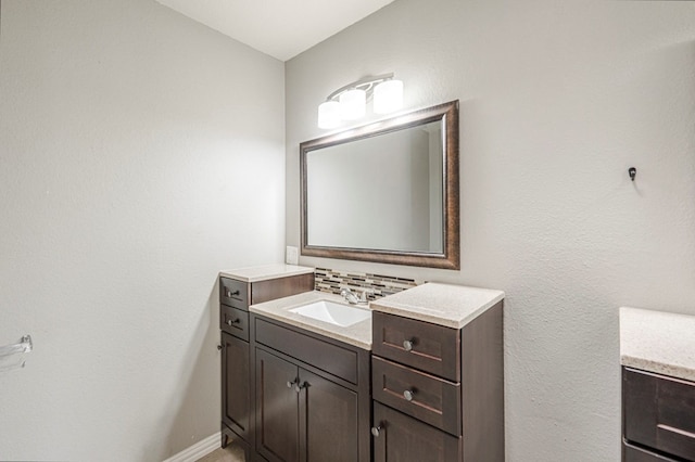 bathroom with tasteful backsplash, baseboards, and vanity