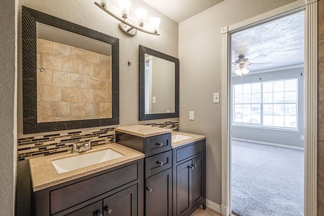 bathroom with baseboards, decorative backsplash, a textured wall, ceiling fan, and vanity