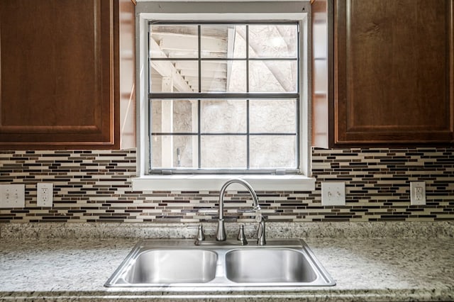 kitchen featuring tasteful backsplash, a sink, and light stone counters