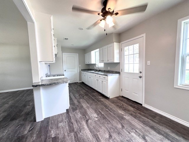 kitchen with baseboards, ceiling fan, white cabinetry, a sink, and dark wood finished floors