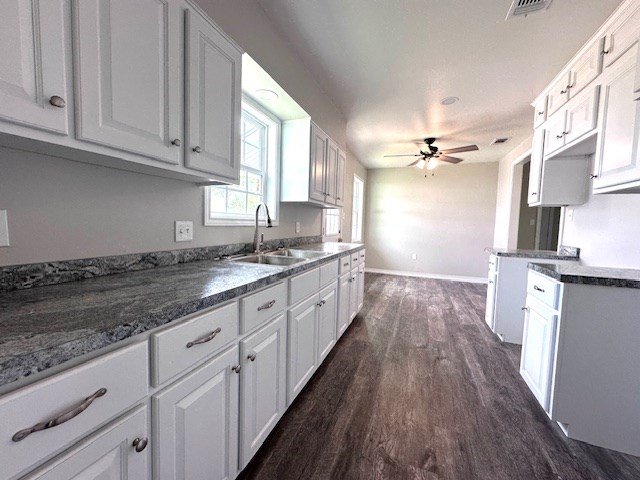 kitchen featuring ceiling fan, visible vents, dark wood finished floors, a sink, and white cabinets