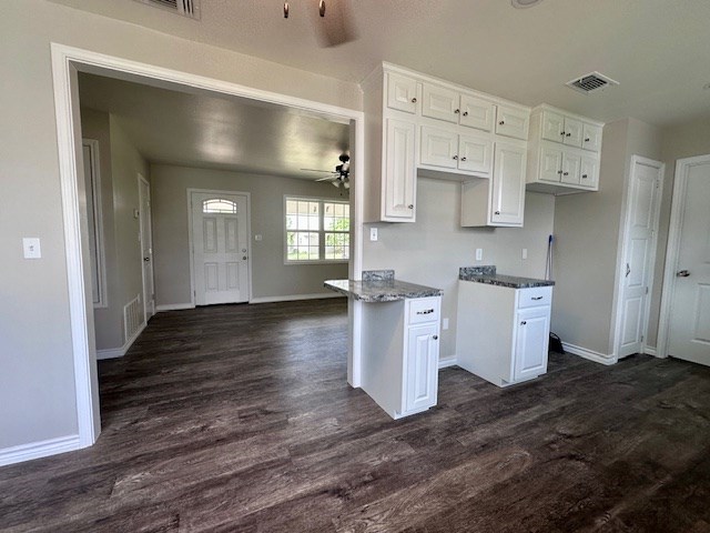 kitchen featuring dark wood-style flooring, baseboards, visible vents, and white cabinetry